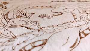 A close up photo of an intricate laser etching of what looks like a hand-drawn dragon. The very narrow depth of field causes the top and bottom of the image to be blurred leaving only the centre in focus.