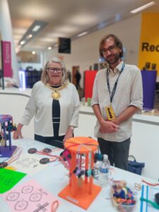 Jake and Lord Mayor Barbara, standing behind a table with a selection of braiding equipment
