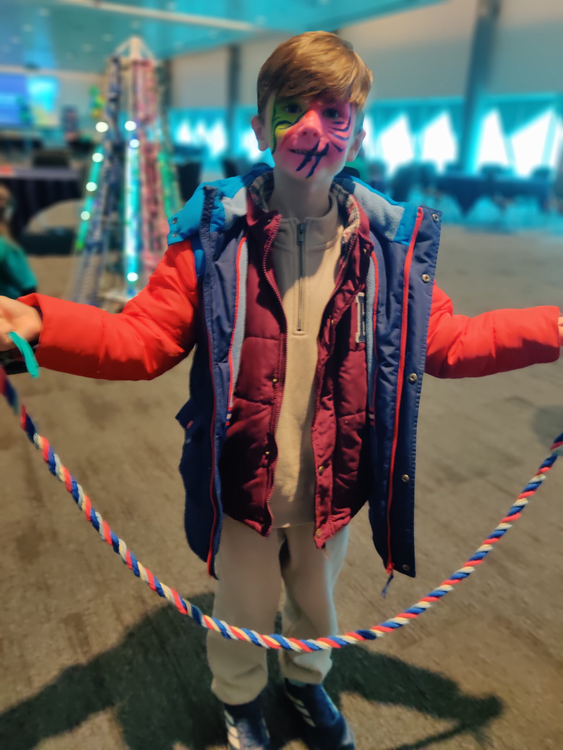 Boy, with face paint, holding a t shirt yarn rope